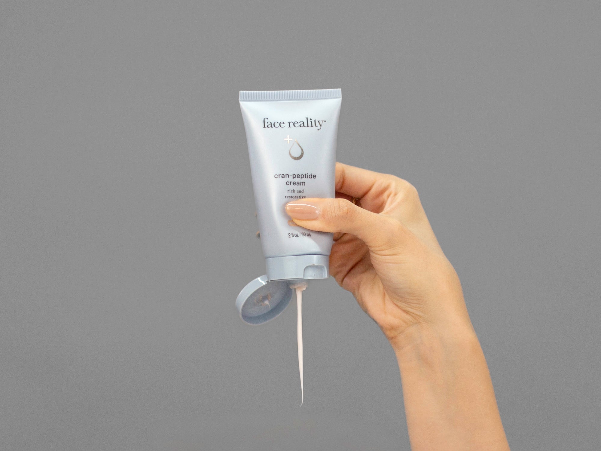 Closeup of Laziza from LAZ Skincare squeezing a tube of Face Reality Cran-Peptide Cream