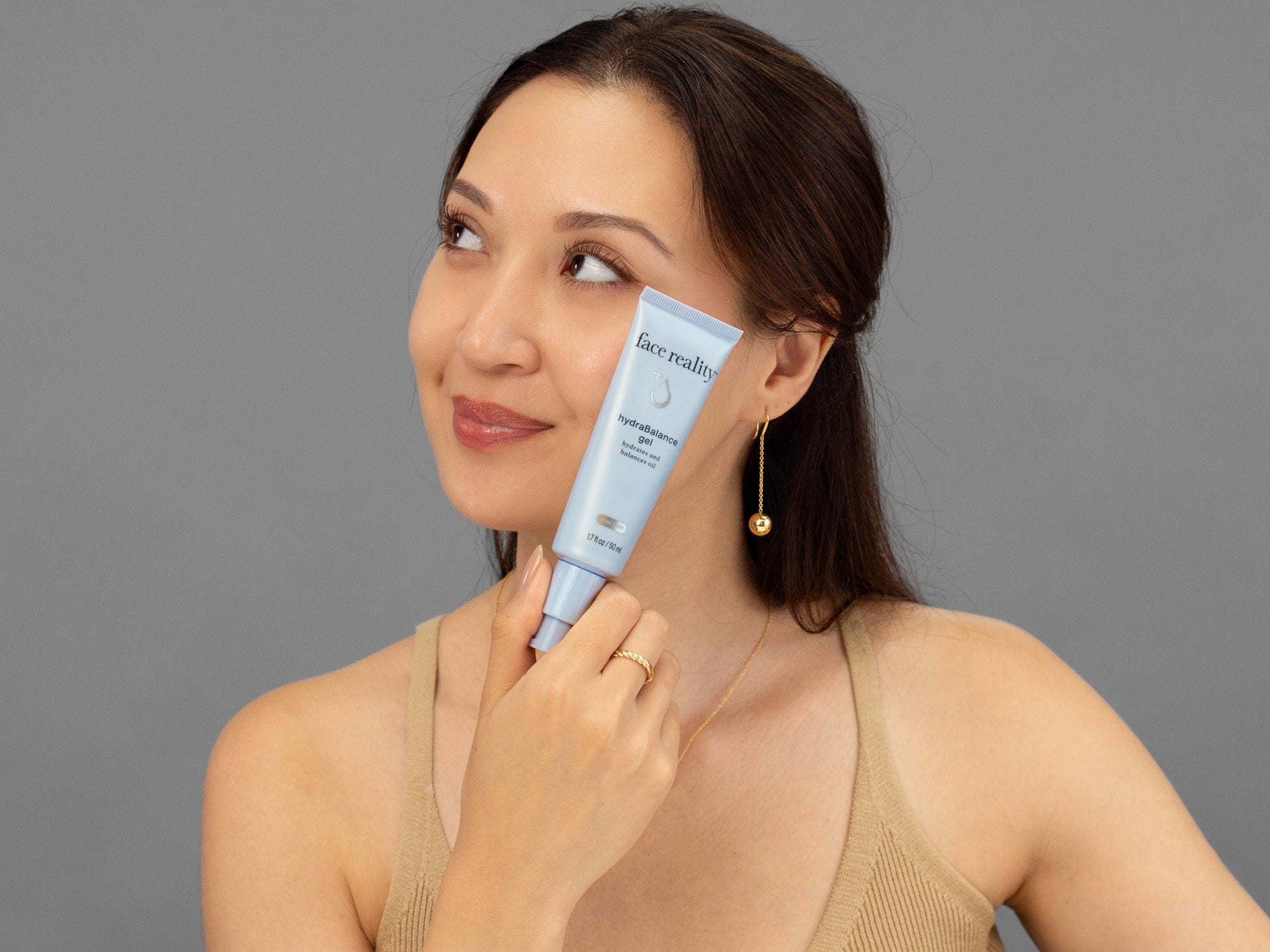 Laziza from LAZ Skincare holding a tube of Face Reality HydraBalance Gel up to her face