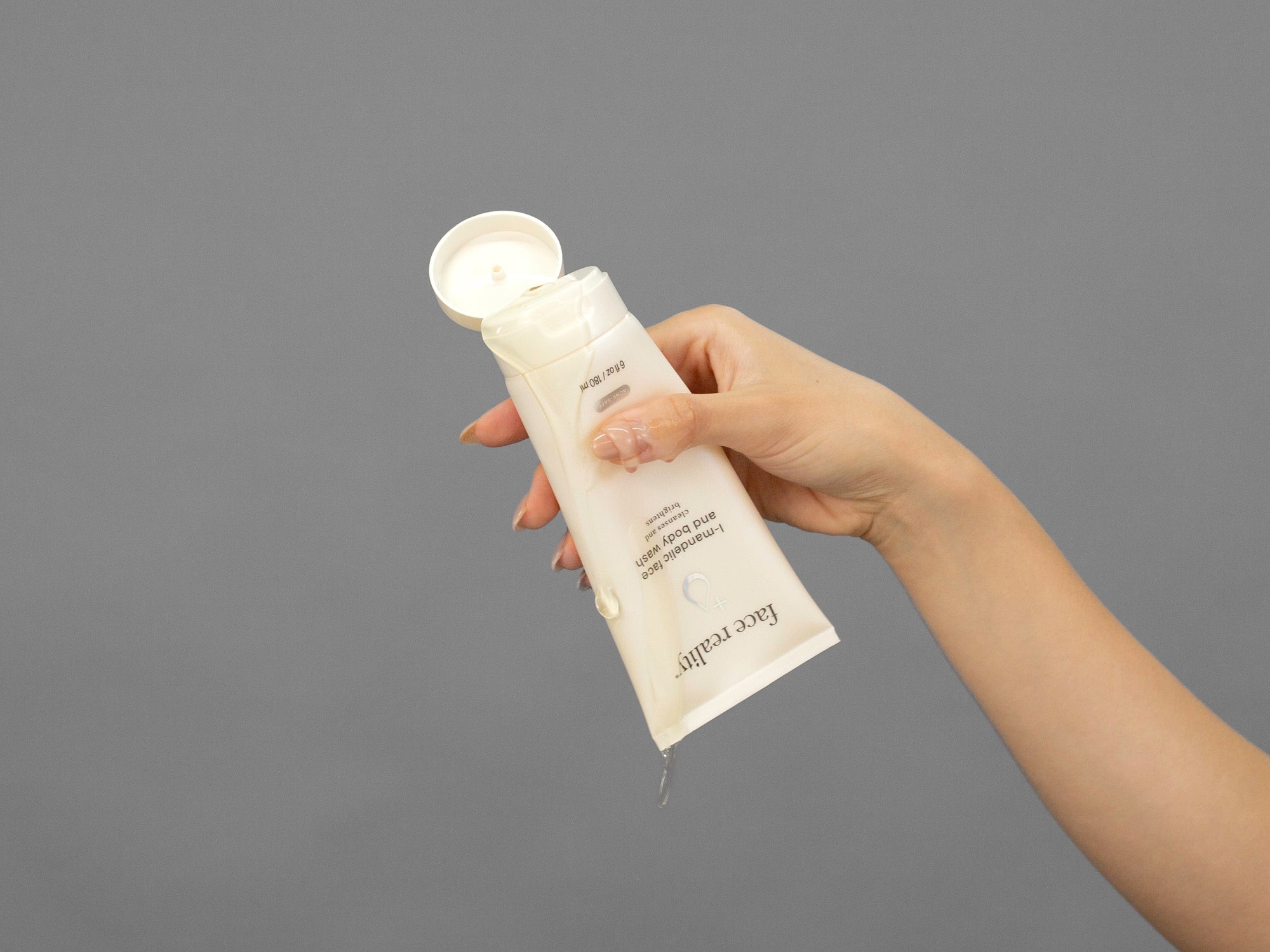 Closeup of Laziza from LAZ Skincare squeezing a tube of Face Reality Mandelic Face & Body Wash in her hand