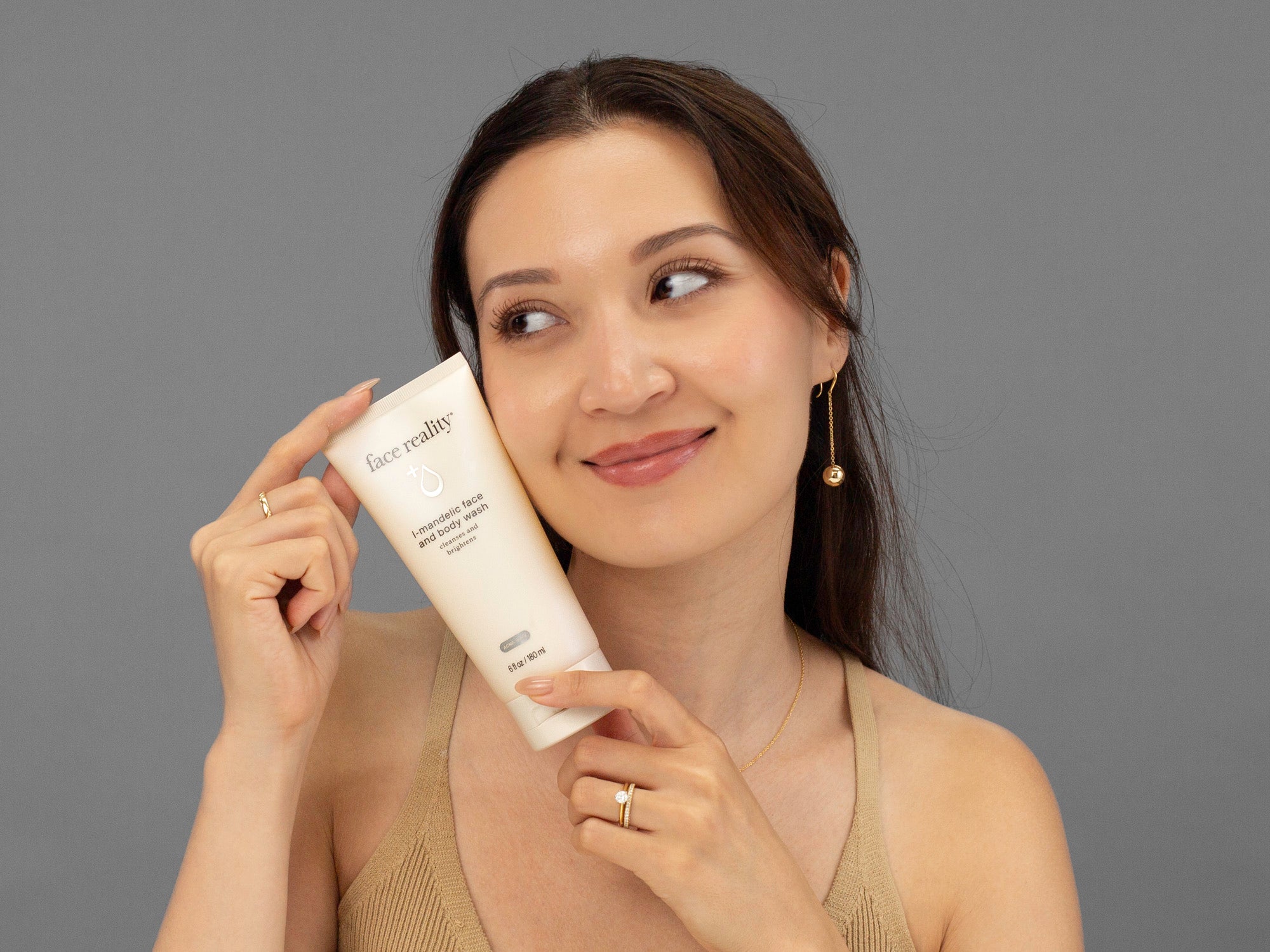 Laziza from LAZ Skincare holding a tube of Face Reality Mandelic Face & Body Wash up to her face
