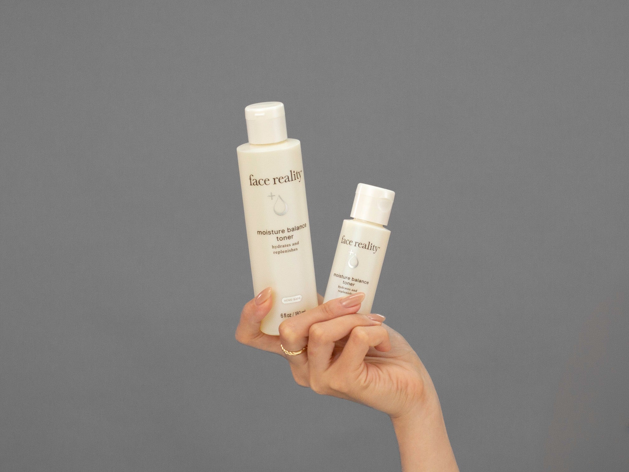 Closeup of Laziza from LAZ Skincare holding both sizes of Face Reality Moisture Balance Toner bottles