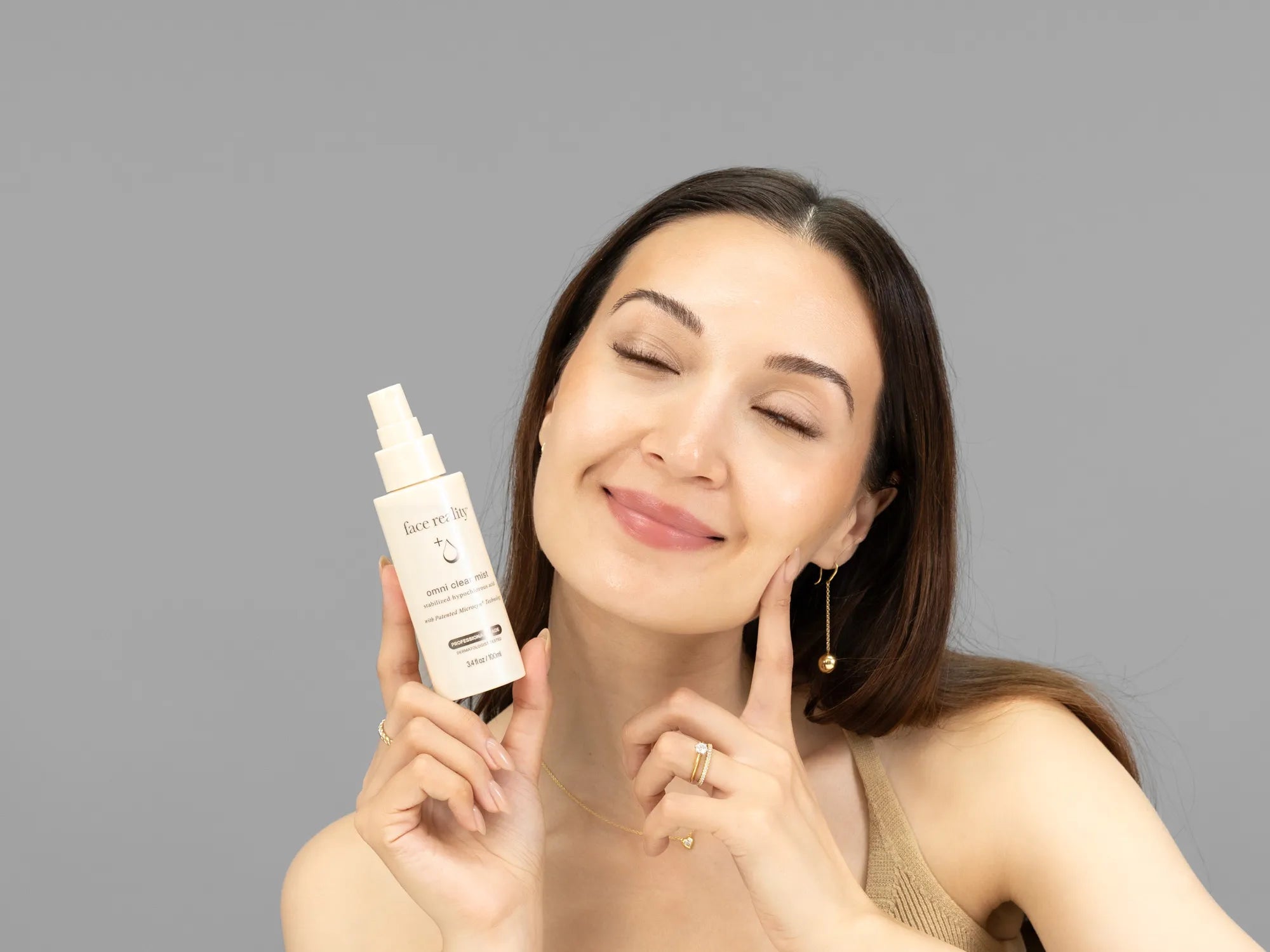 Laziza from LAZ Skincare holding a bottle of Face Reality Omni Clear Mist up to her face