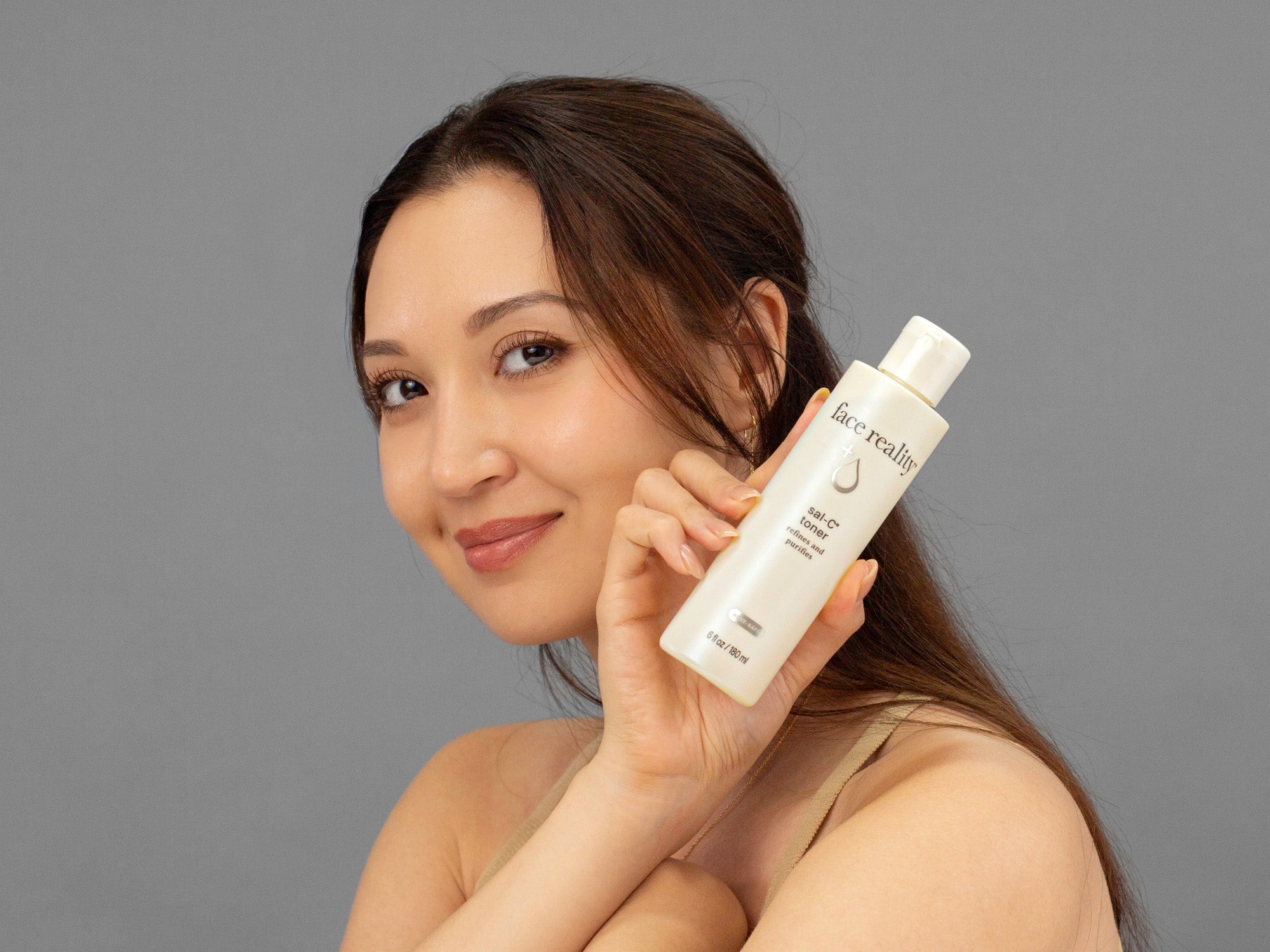 Laziza from LAZ Skincare holding up a bottle of Face Reality Sal-C Toner up to her face