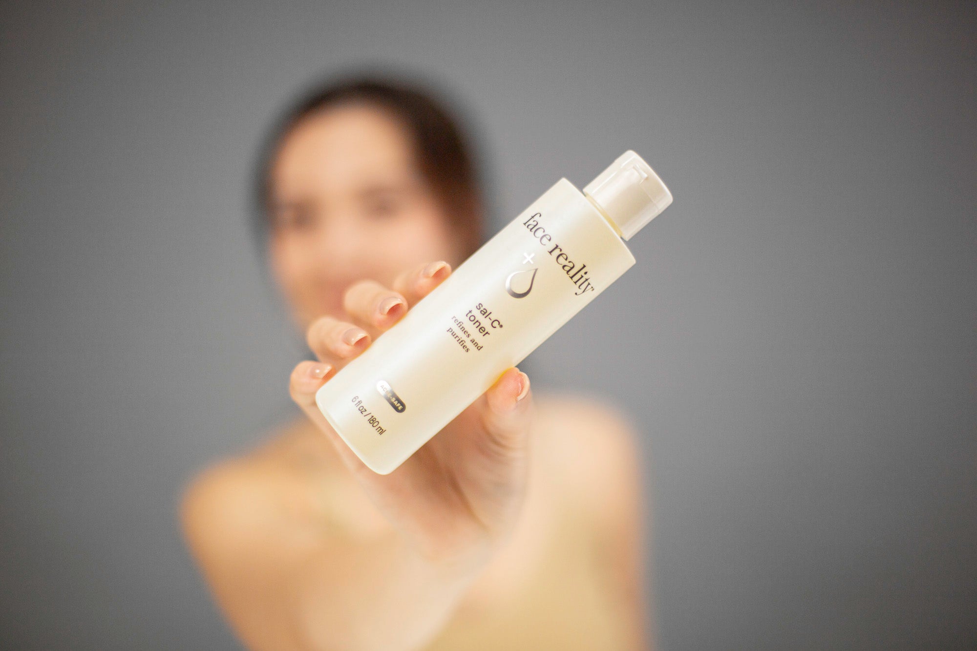 Laziza from LAZ Skincare holding up a bottle of Face Reality Sal-C Toner with a blurred background