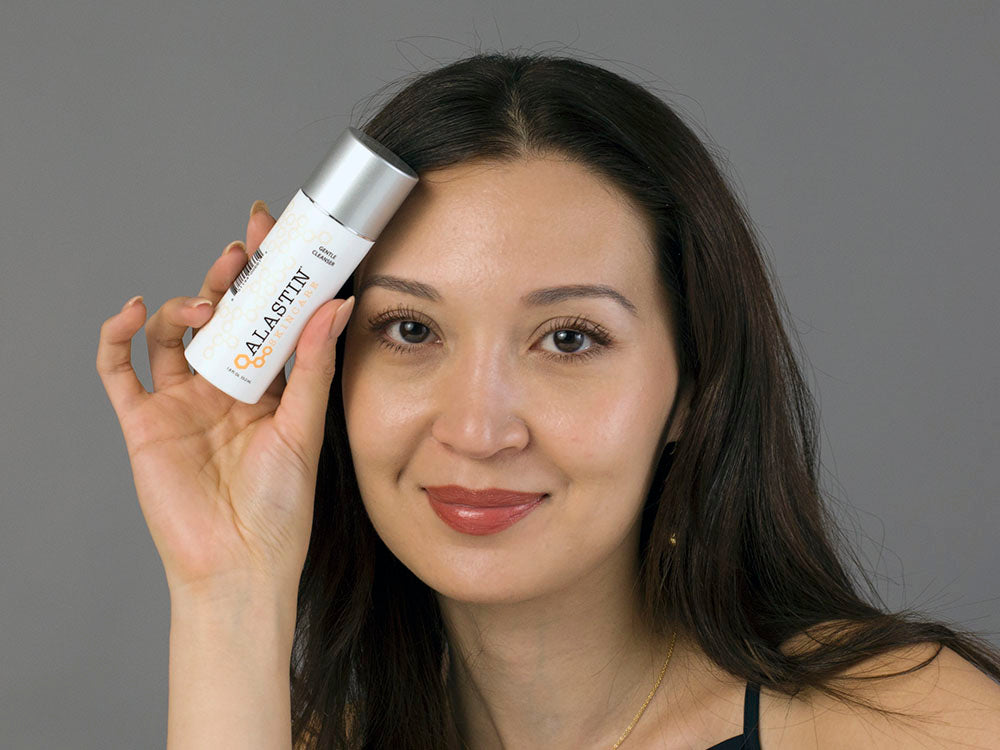 Laziza from LAZ Skincare holding a bottle of Alastin Gentle Cleanser up to her face