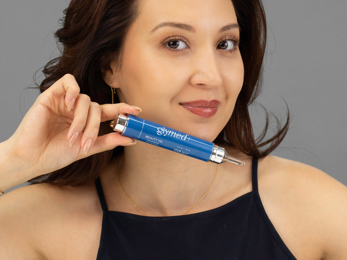 Laziza from LAZ Skincare holding a bottle of GlyMed Beauty Oil up to her face