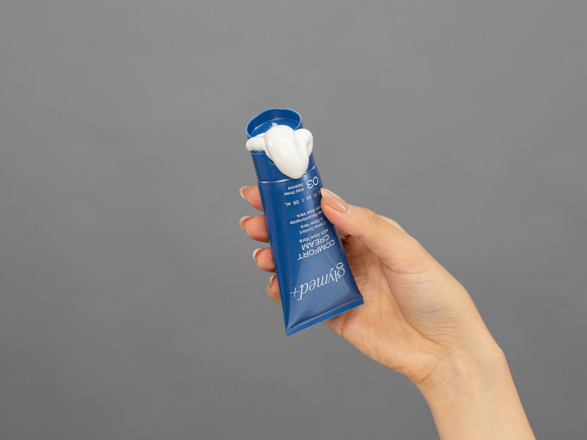 Closeup of Laziza from LAZ Skincare squeezing a tube of GlyMed Comfort Cream in her hand