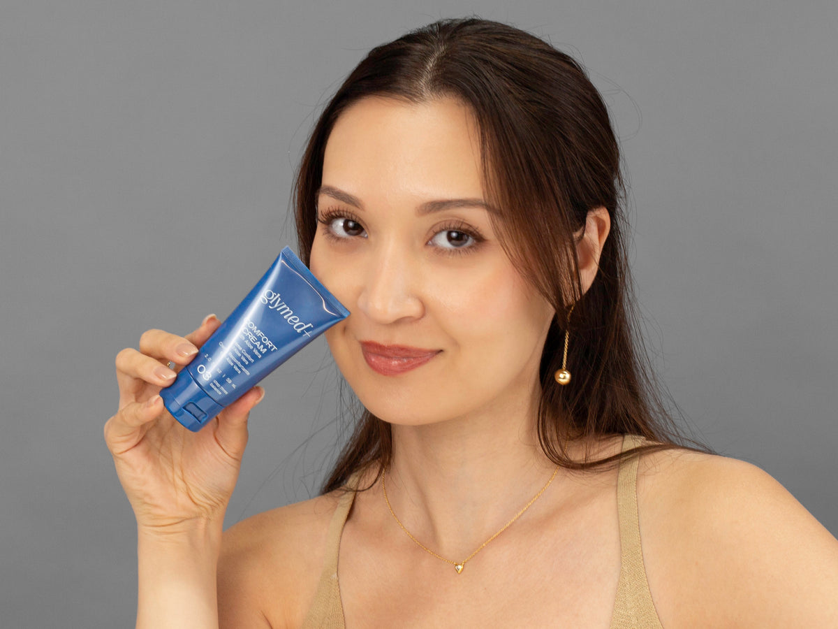 Laziza from LAZ Skincare holding a bottle of GlyMed Comfort Cream up to her face