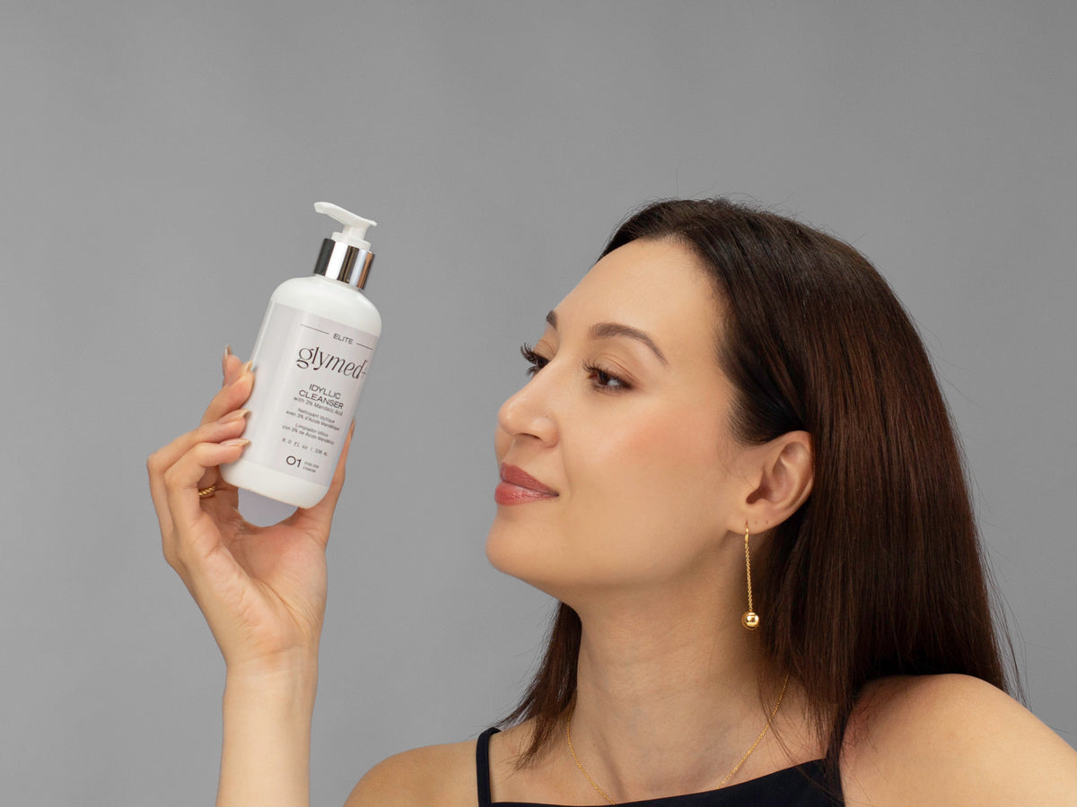 Laziza from LAZ Skincare holding a bottle of GlyMed Idyllic Cleanser up to her face