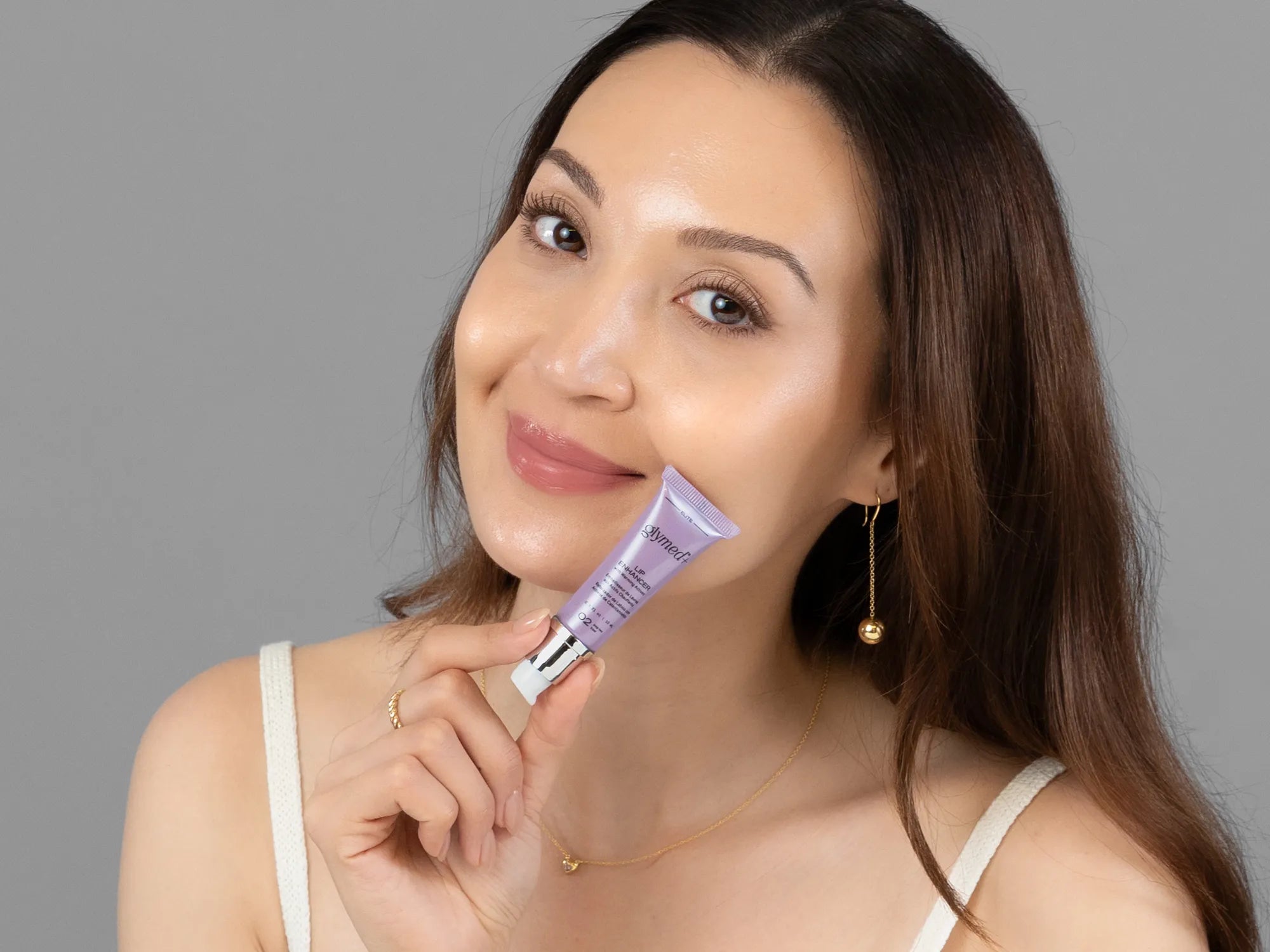 Laziza from LAZ Skincare holding a bottle of GlyMed Lip Enhancer up to her face