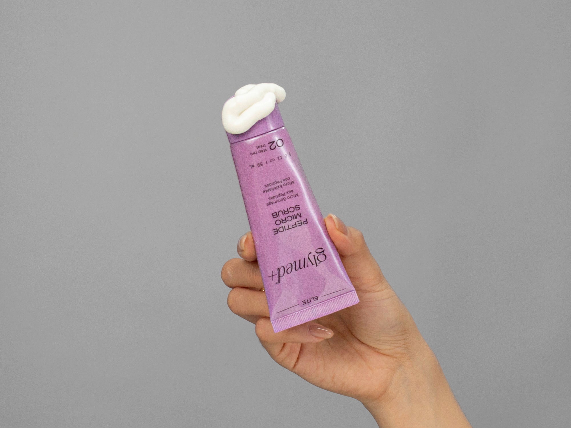 Closeup of Laziza from LAZ Skincare holding a tube of GlyMed Peptide Micro Scrub in her hand