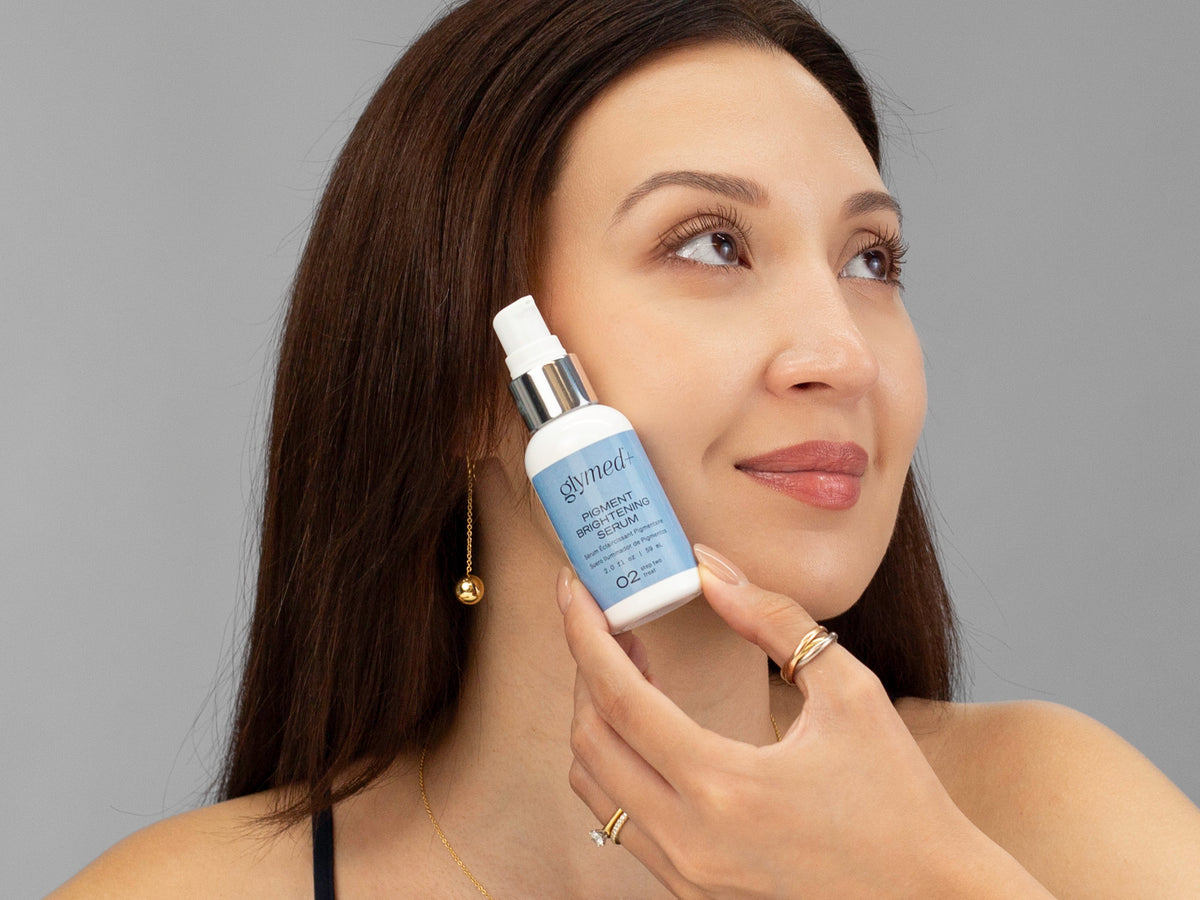 Laziza from LAZ Skincare holding a bottle of GlyMed Pigment Brightening Serum up to her face