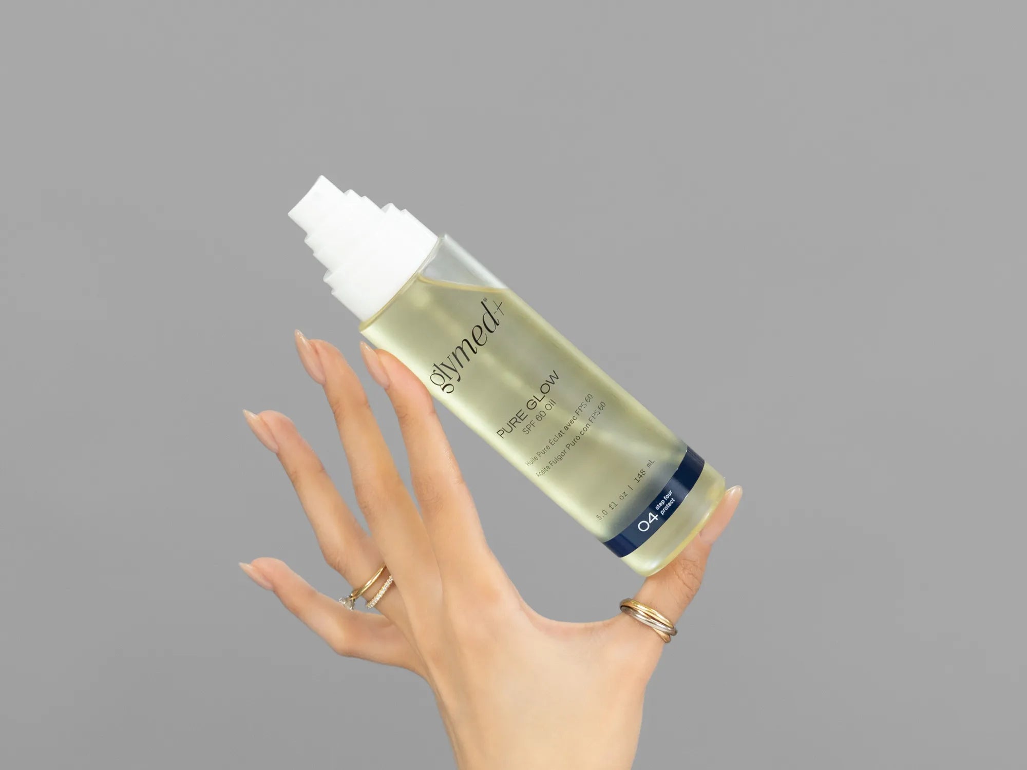 Closeup of Laziza from LAZ Skincare holding up a bottle of GlyMed Pure Glow SPF 60 Oil