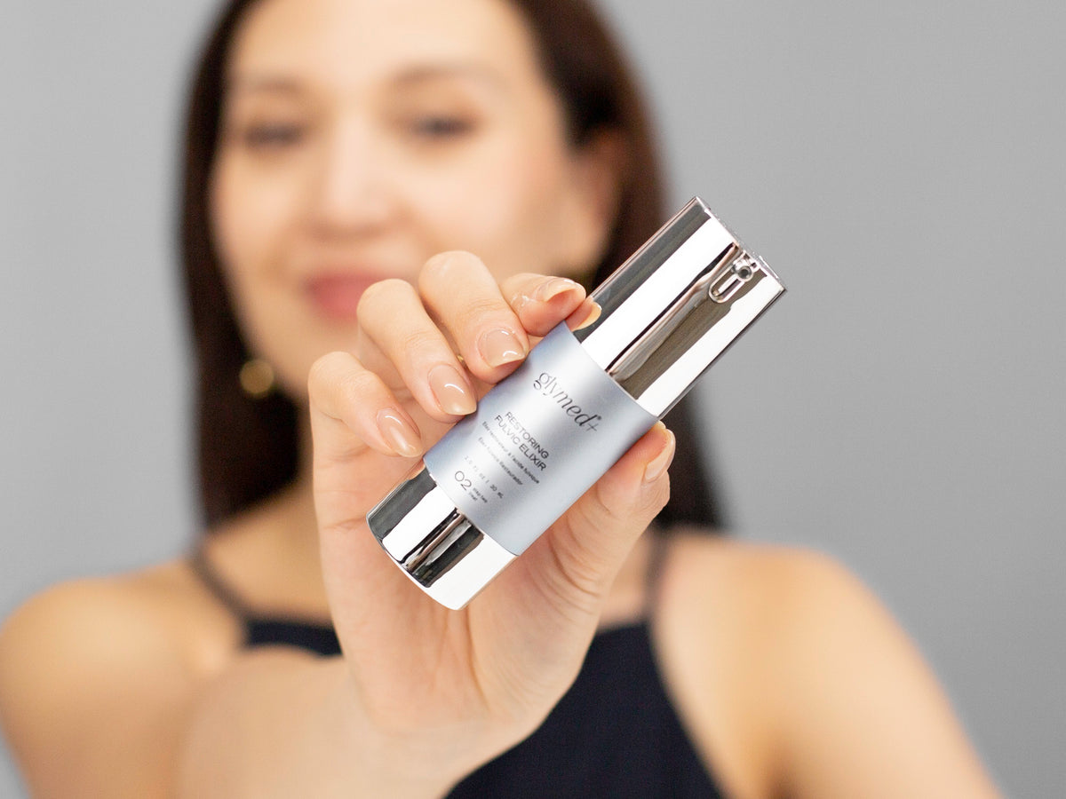 Laziza from LAZ Skincare holding a bottle of GlyMed Restoring Fulvic Elixir up to her face