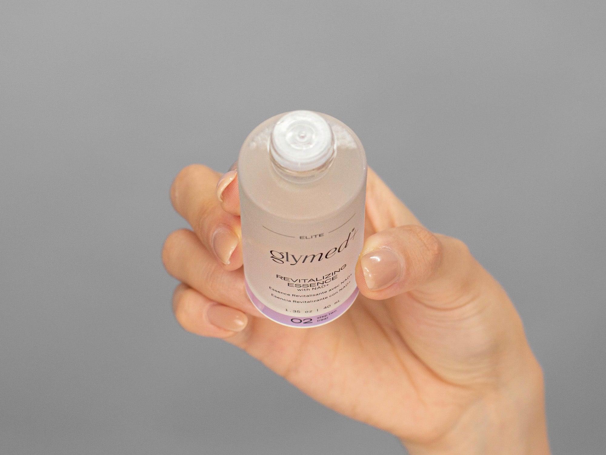 Closeup of Laziza from LAZ Skincare holding a bottle of GlyMed Revitalizing Essence in her hand