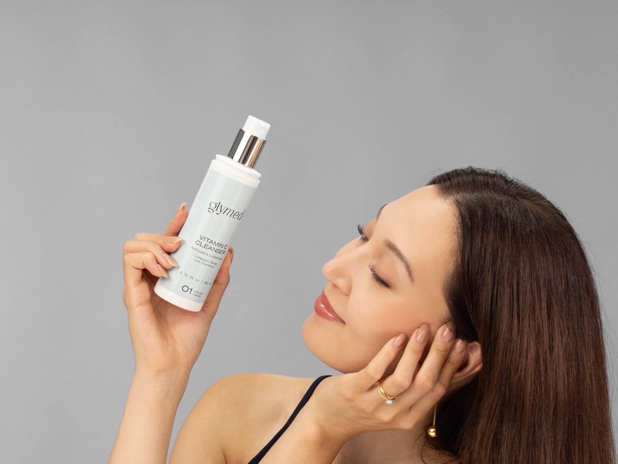 Laziza from LAZ Skincare holding a bottle of GlyMed Vitamin C Cleanser up to her face