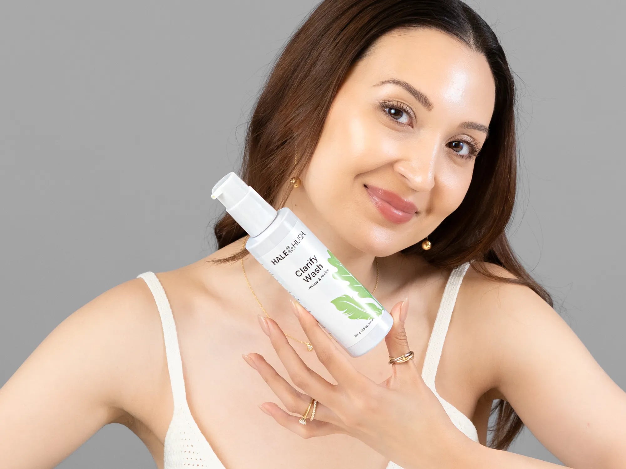 Laziza from LAZ Skincare holding a bottle of Hale & Hush Clarify Wash up to her face