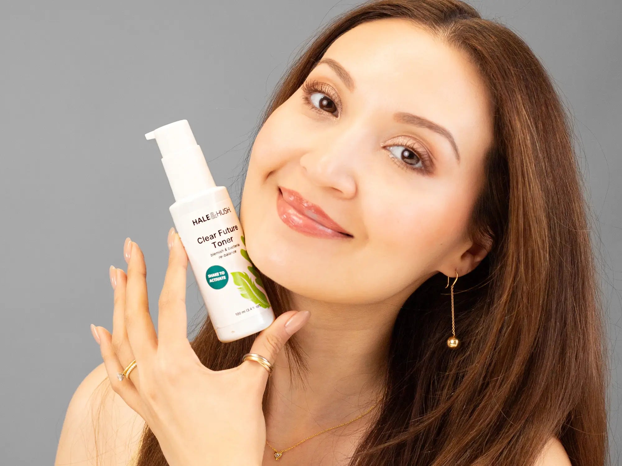 Laziza from LAZ Skincare holding a bottle of Hale & Hush Clear Future Toner up to her face