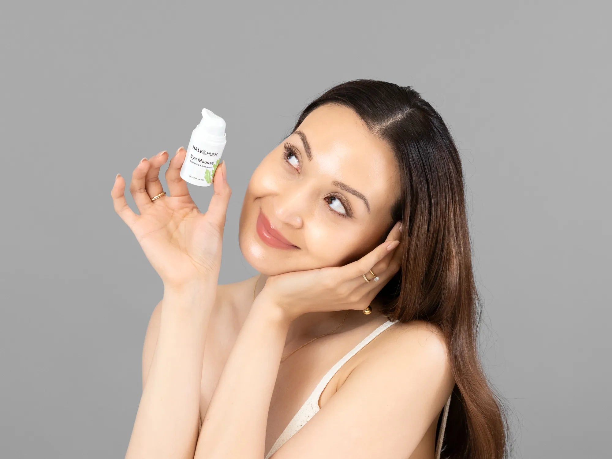 Laziza from LAZ Skincare holding a bottle of Hale & Hush Eye Mousse up to her face