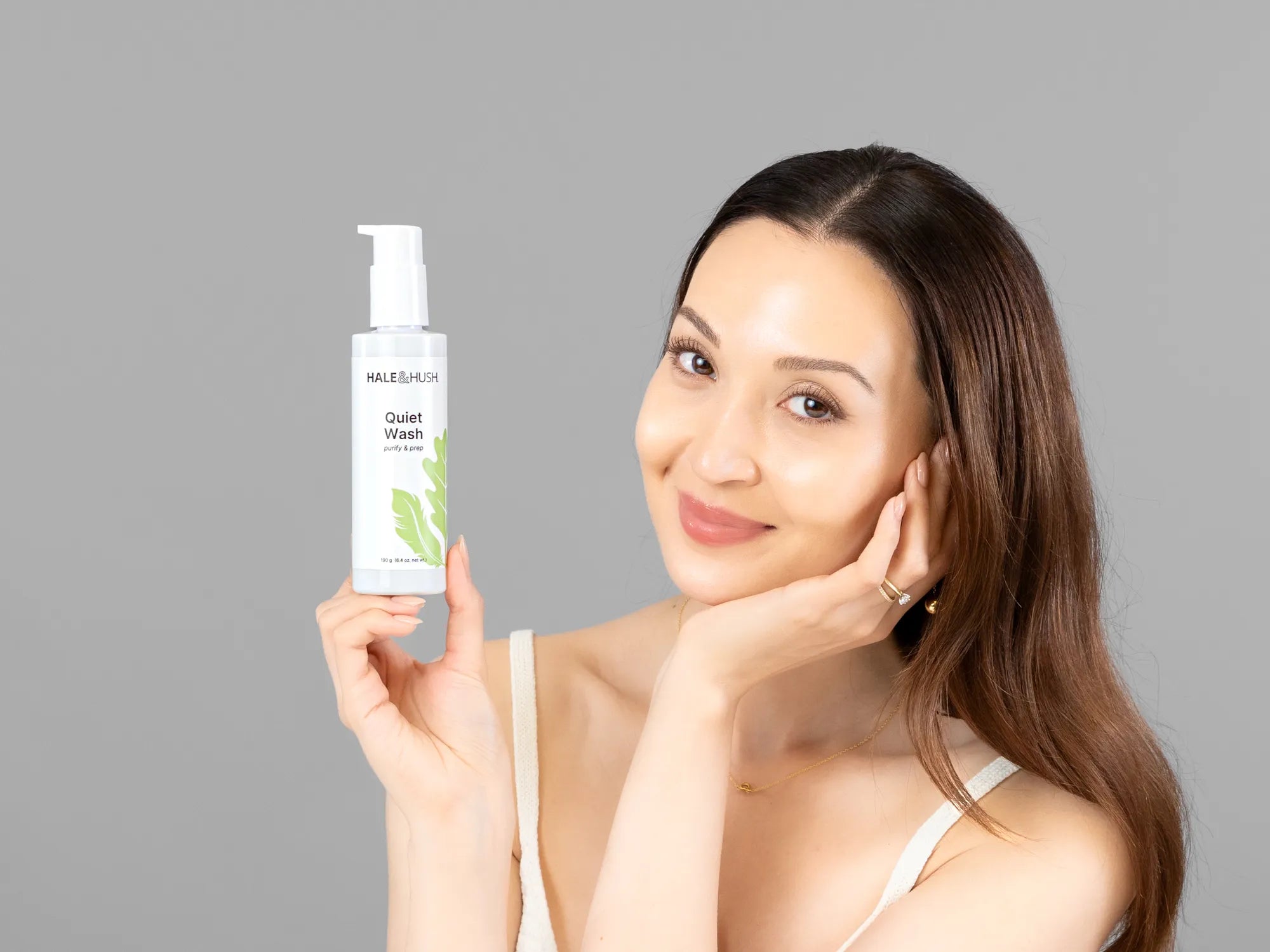 Laziza from LAZ Skincare holding a bottle of Hale & Hush Quiet Wash up to her face