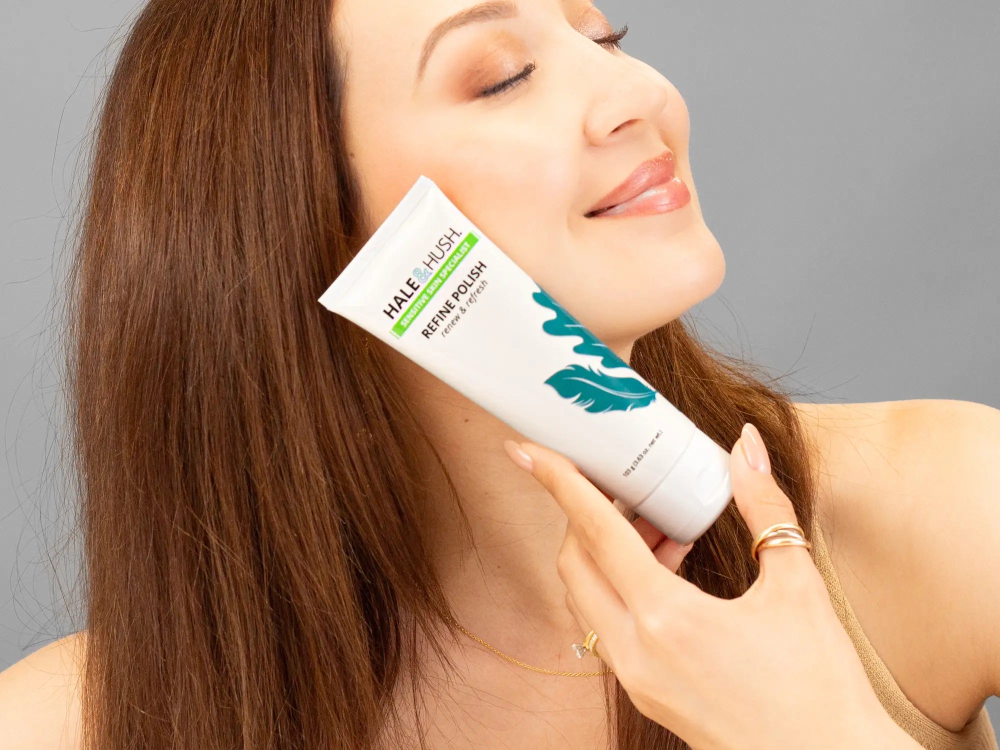 Laziza from LAZ Skincare holding a bottle of Hale & Hush Refine Polish up to her face