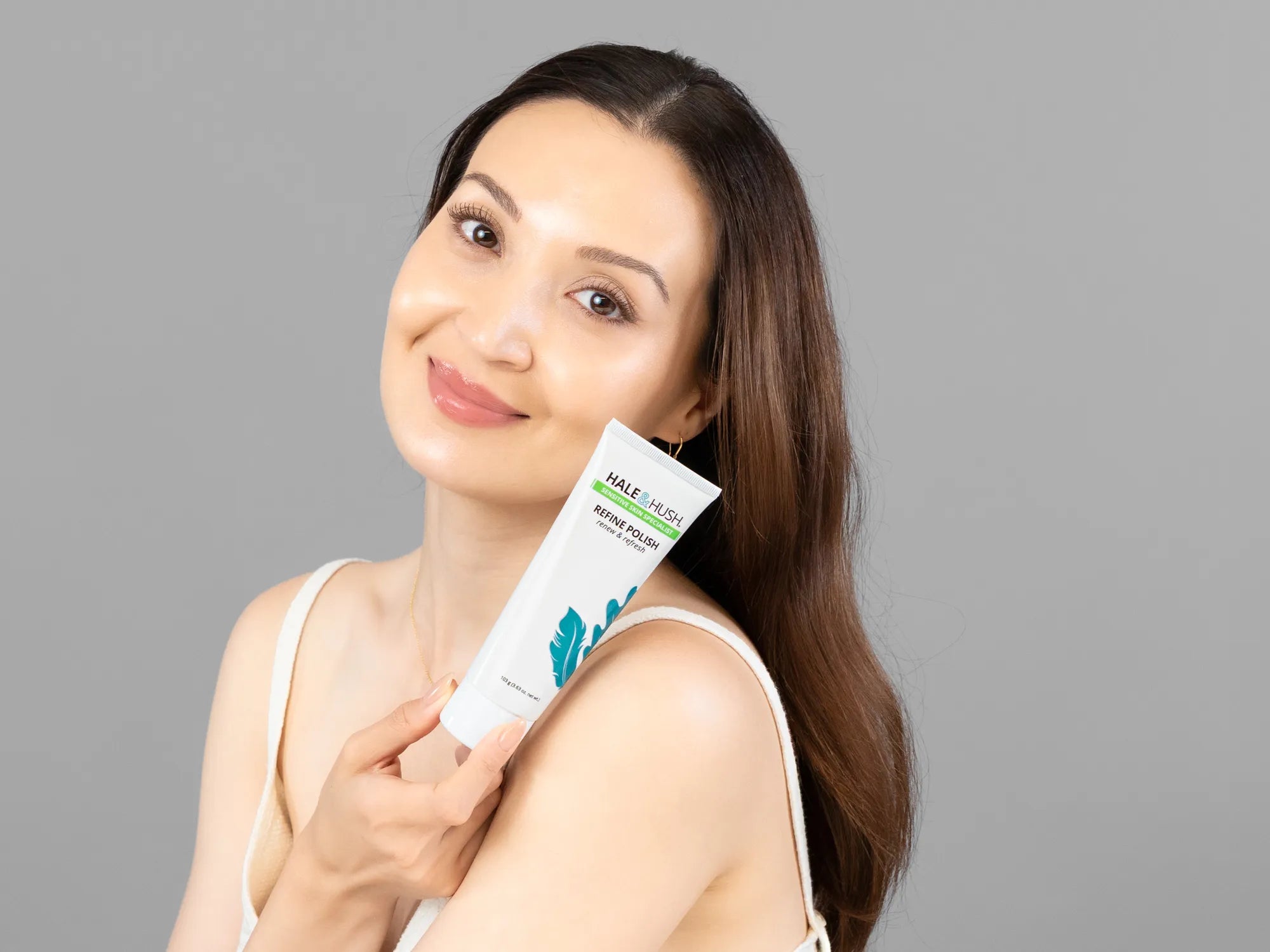 Laziza from LAZ Skincare holding a bottle of Hale & Hush Refine Polish up to her face