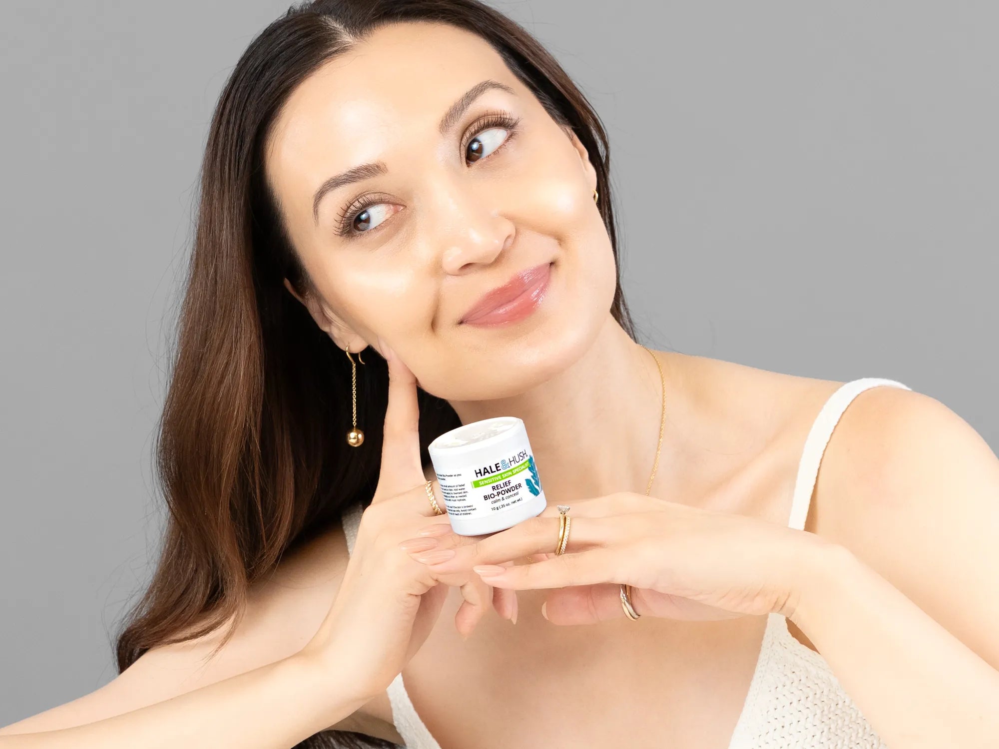 Laziza from LAZ Skincare holding a bottle of Hale & Hush Relief Bio-Powder up to her face