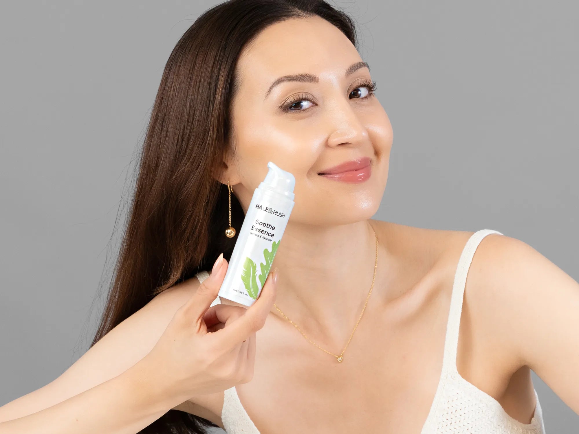 Laziza from LAZ Skincare holding a bottle of Hale & Hush Soothe Essence Serum up to her face