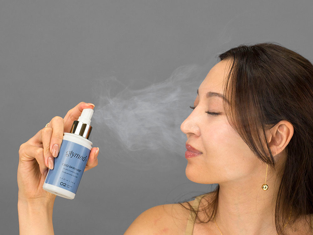 Laziza from LAZ Skincare holding a bottle of GlyMed Hemp Skin Mist up to her face