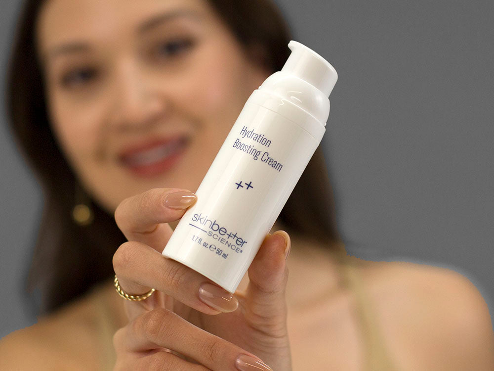 Laziza from LAZ Skincare holding a bottle of SkinBetter Science Hydration Boosting Cream up to her face