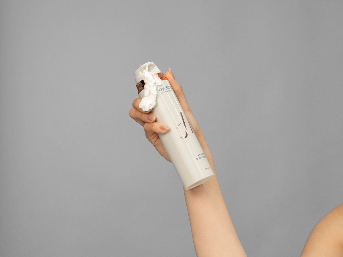 Closeup of Laziza from LAZ Skincare holding up a bottle of Hydrinity Encore Body Hydrator