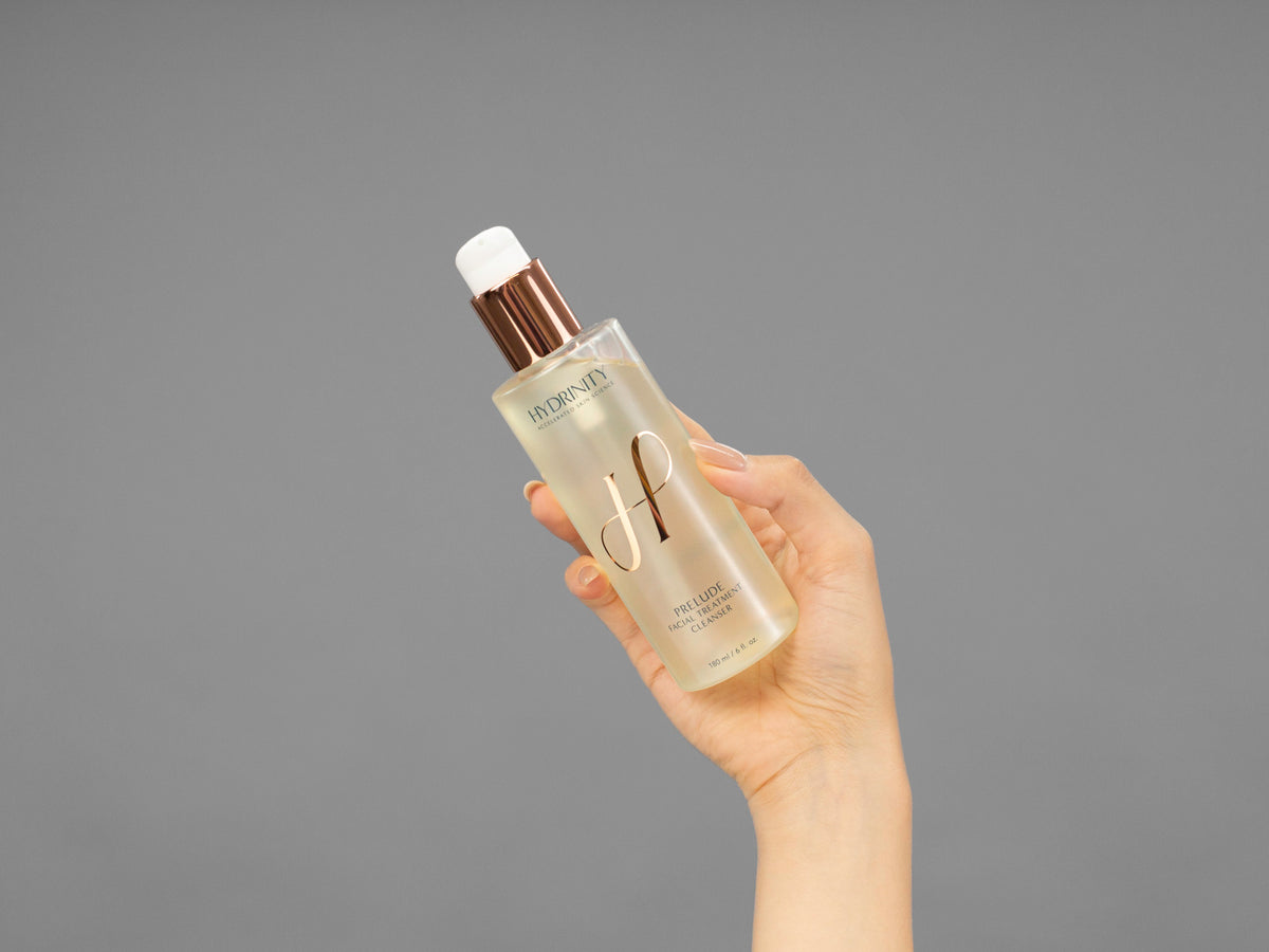 Closeup of Laziza from LAZ Skincare holding up a bottle of Hydrinity Prelude Facial Treatment Cleanser