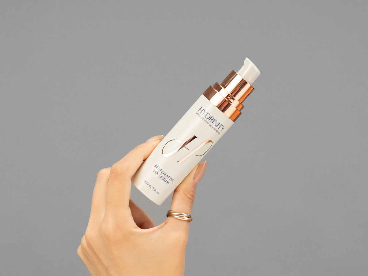 Closeup of Laziza from LAZ Skincare holding up a bottle of Hydrinity Restorative HA Serum