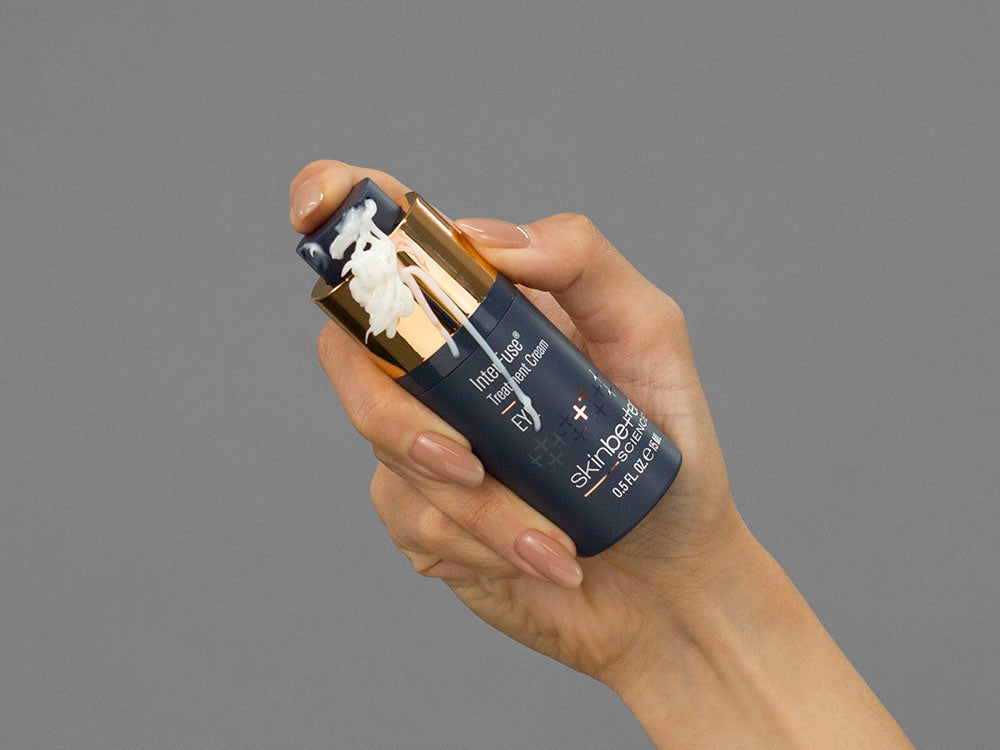 Closeup of Laziza from LAZ Skincare holding up a bottle of SkinBetter Science InterFuse Treatment Cream EYE
