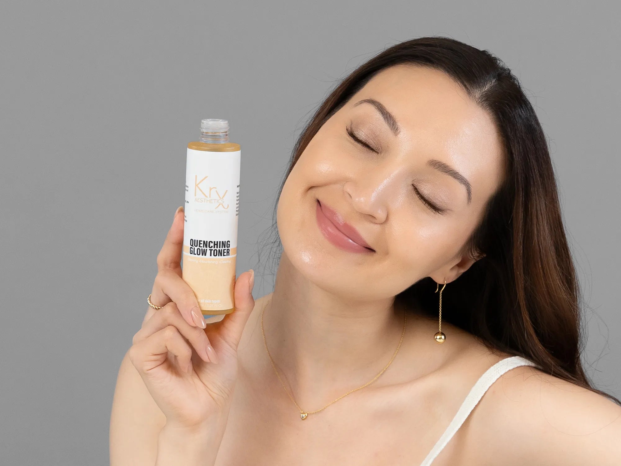 Laziza from LAZ Skincare holding a bottle of KrX Aesthetics Quenching Glow Toner up to her face