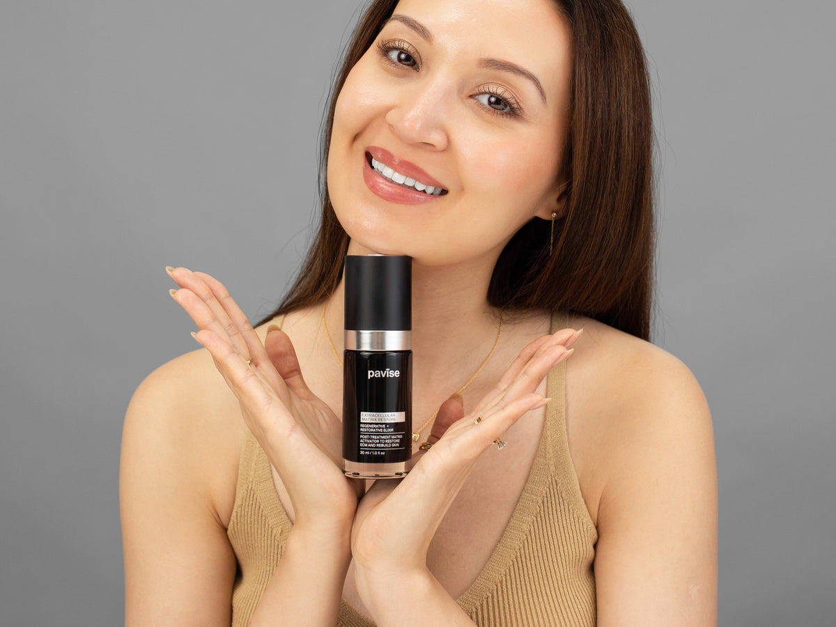 Laziza from LAZ Skincare holding a bottle of Pavise Extracellular Matrix Restore up to her face