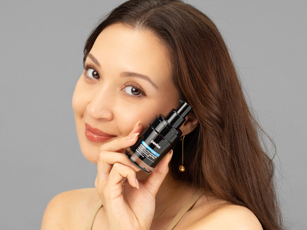 Laziza from LAZ Skincare holding a bottle of Pavise Precision Eye Lift up to her face