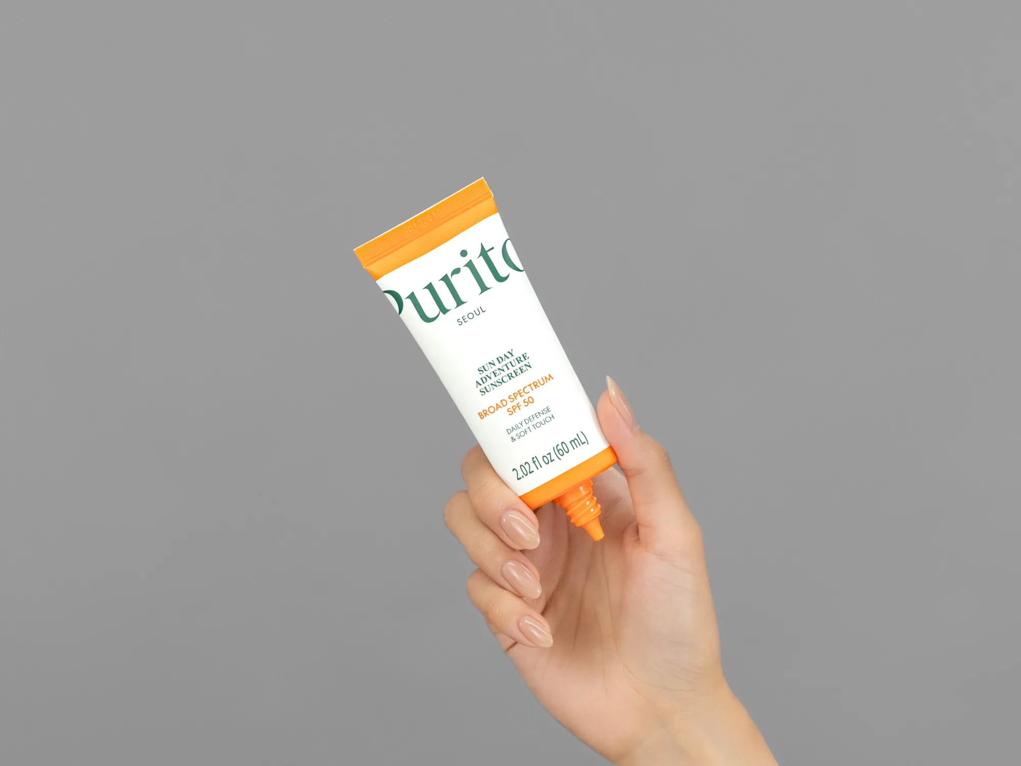 Closeup of Laziza from LAZ Skincare holding up a bottle of Purito Seoul Sun Day Adventure Sunscreen