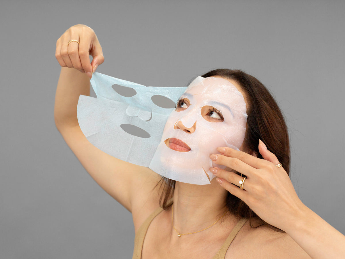 Laziza from LAZ Skincare holding a bottle of Hydrinity Restorative HA+ Mask up to her face