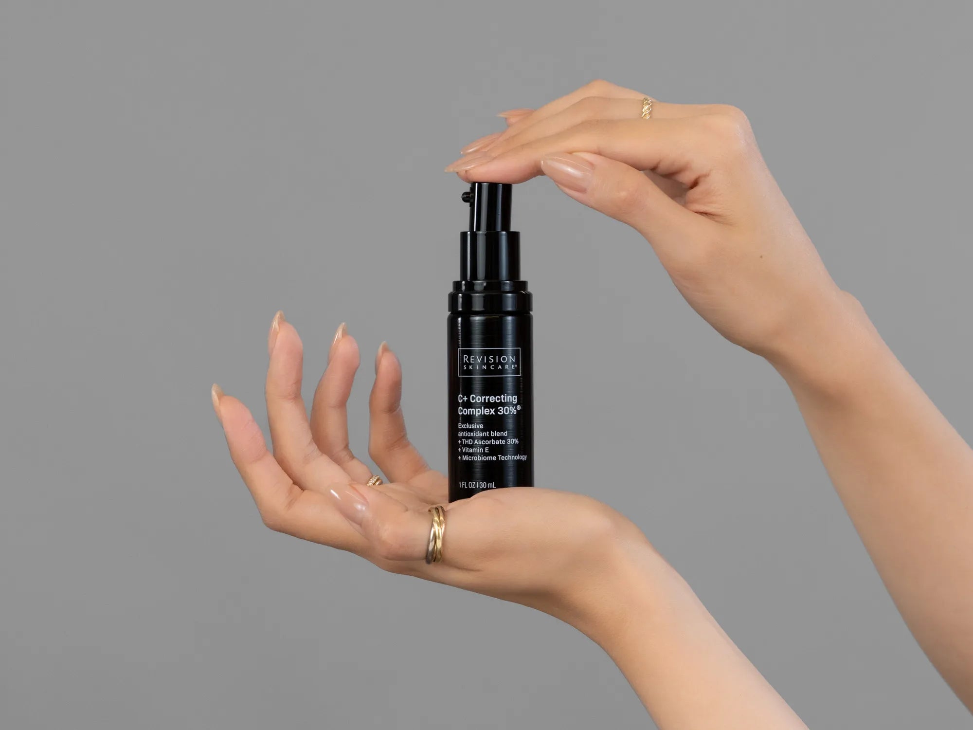 Closeup of Laziza from LAZ Skincare holding up a bottle of Revision C+ Correcting Complex 30%