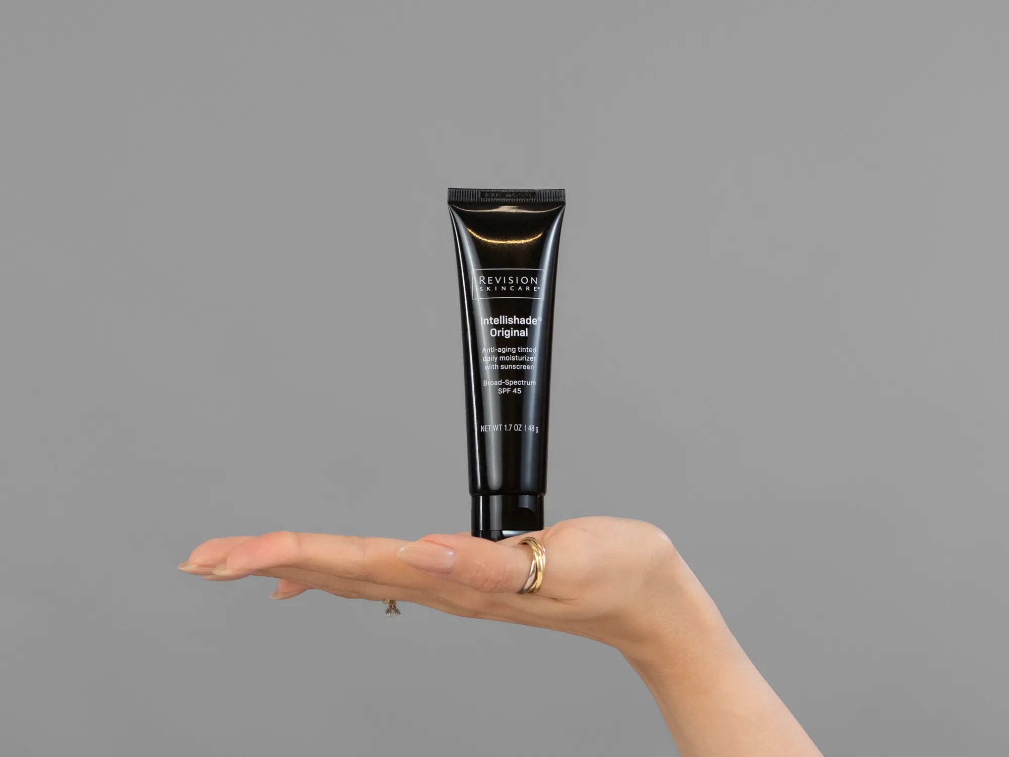 Closeup of Laziza from LAZ Skincare holding up a bottle of Revision Intellishade Original SPF 45