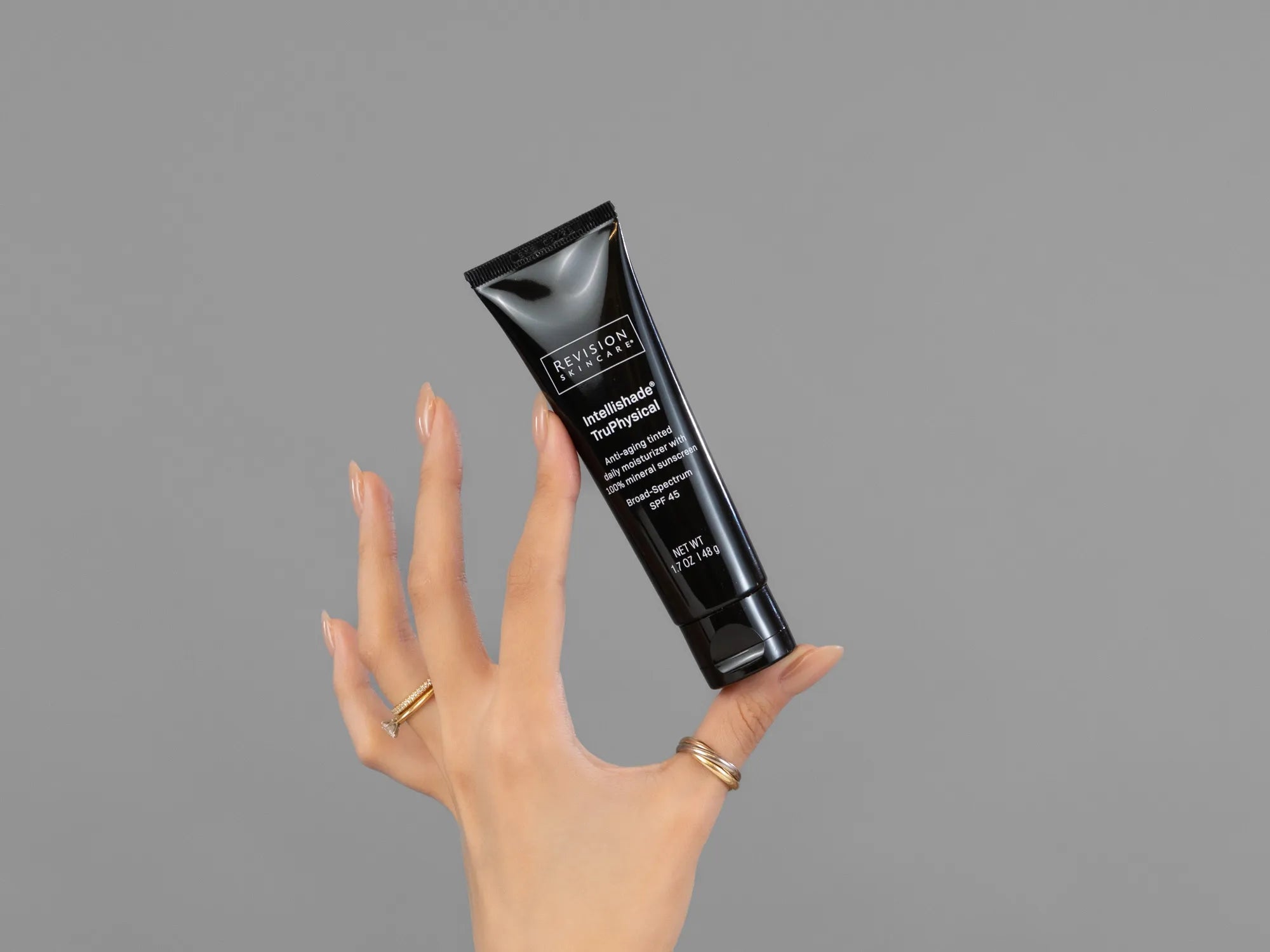Closeup of Laziza from LAZ Skincare holding up a bottle of Revision Intellishade TruPhysical SPF 45