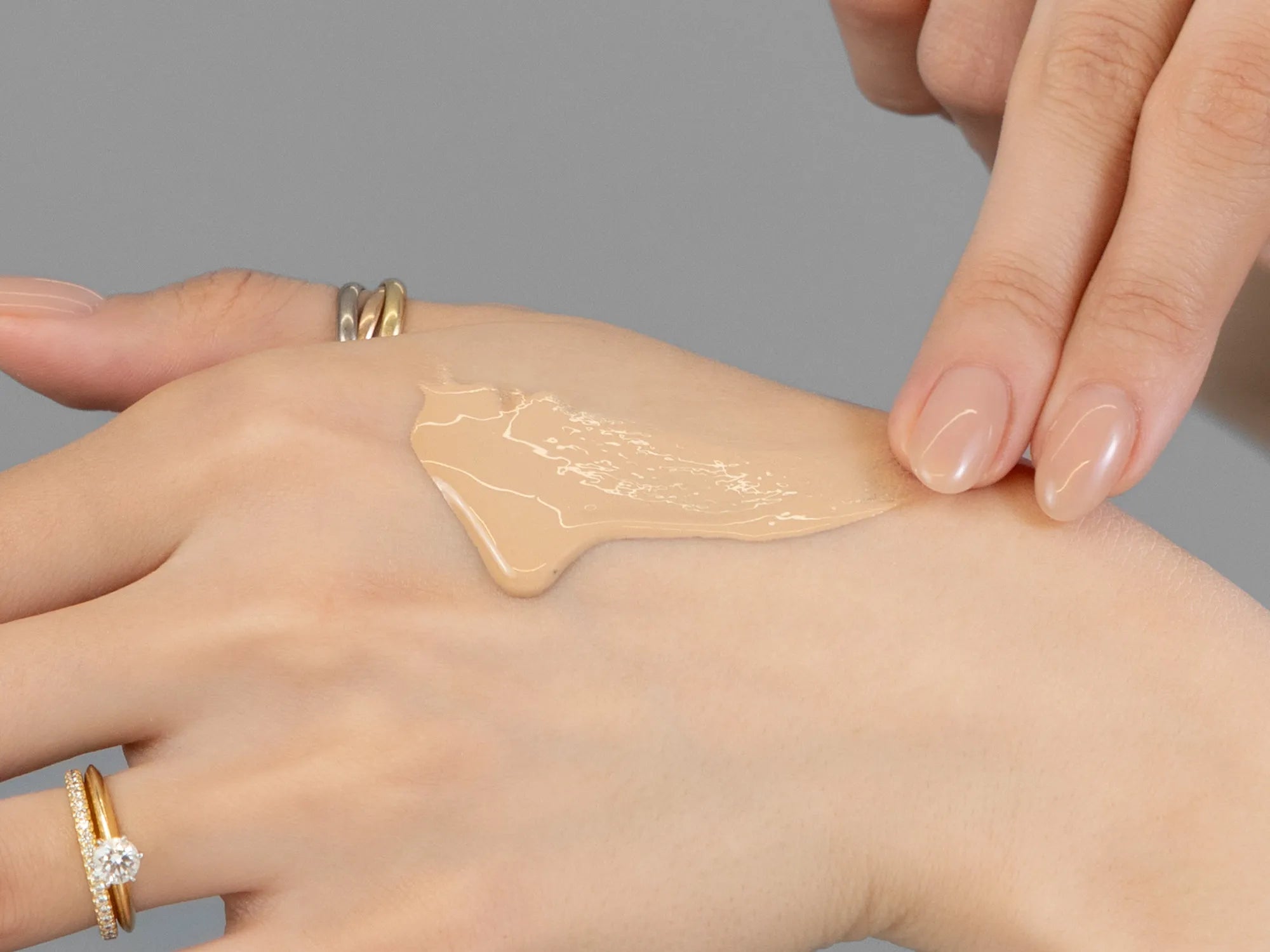 Laziza from LAZ Skincare demonstrating the texture and application of Revision Intellishade TruPhysical SPF 45 on her hand