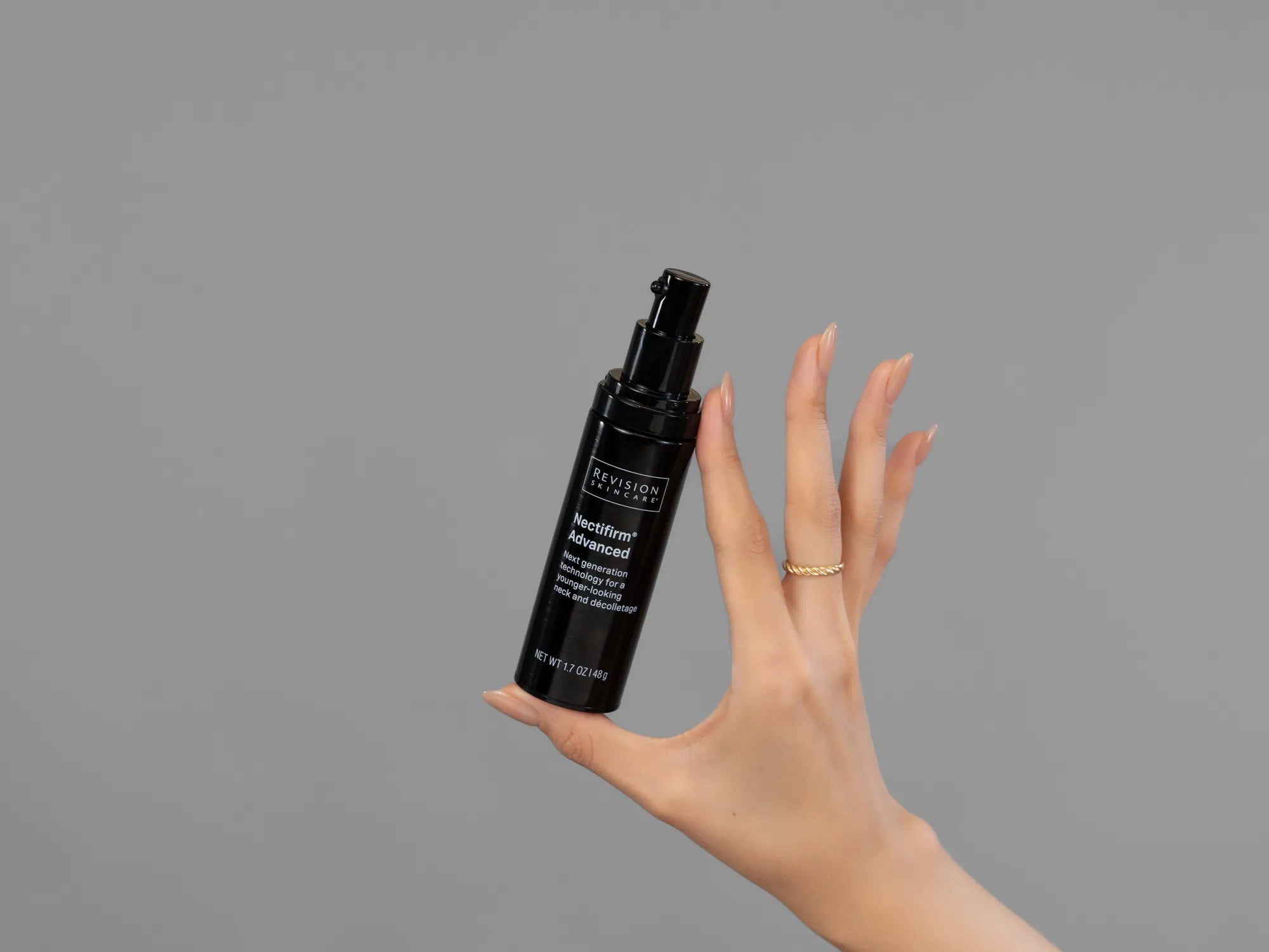 Closeup of Laziza from LAZ Skincare holding up a bottle of Revision Nectifirm Advanced