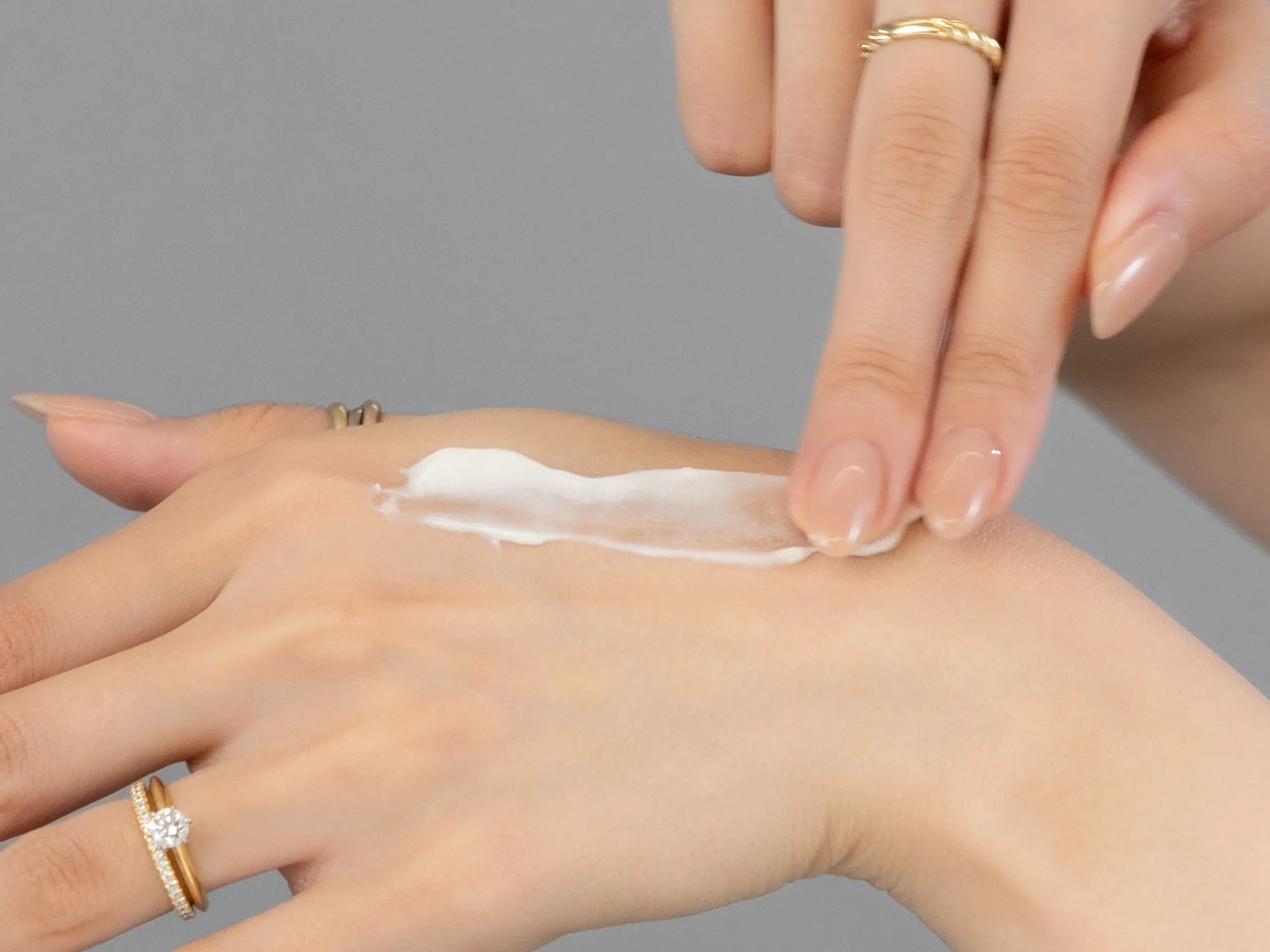 Laziza from LAZ Skincare demonstrating the texture and application of Revision Nectifirm Advanced on her hand