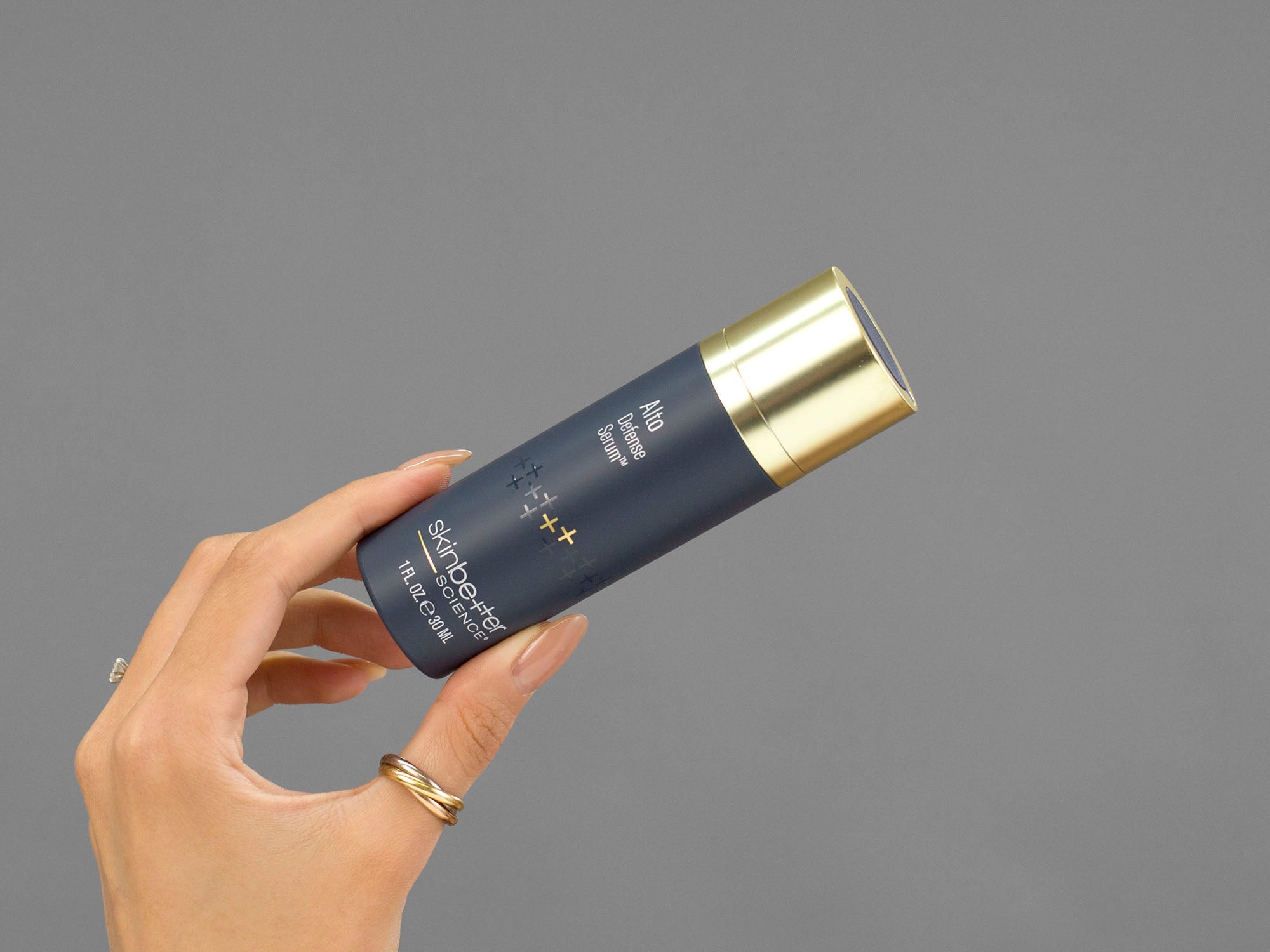 Closeup of Laziza from LAZ Skincare holding a bottle of Skinbetter Science Alto Defense Serum in her hand