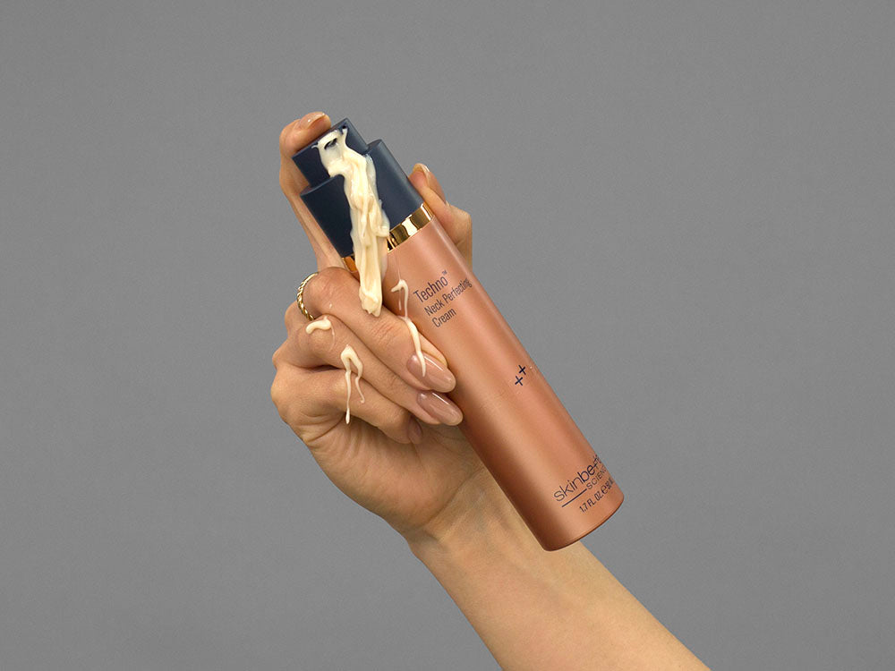 Closeup of Laziza from LAZ Skincare demonstrating the pump on a bottle of Skinbetter Science Techno Neck Perfecting Cream