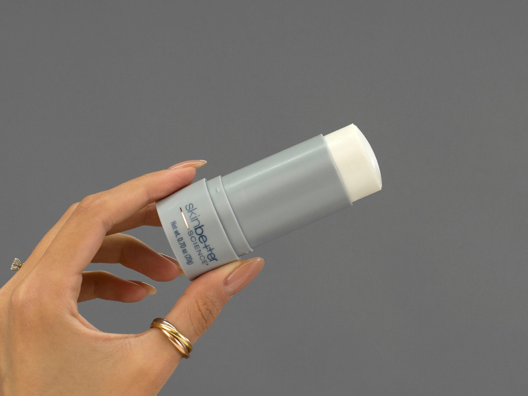 Closeup of Laziza from LAZ Skincare holding an opened stick of Skinbetter Science sunbetter SHEER SPF56 Sunscreen in her hand