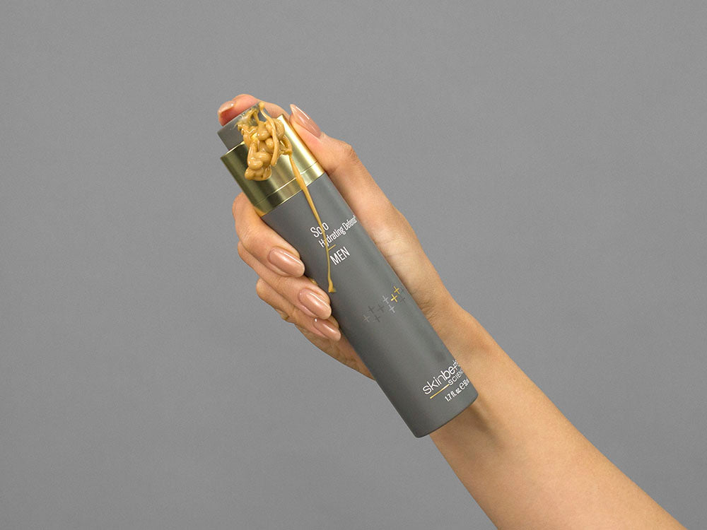 Closeup of Laziza from LAZ Skincare holding up a bottle of SkinBetter Science Solo Hydrating Defense MEN