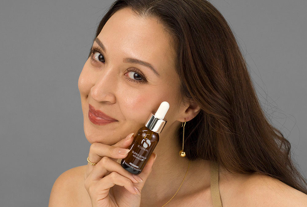 Laziza from LAZ Skincare holding a bottle of iS Clinical Super Serum Advance+ up to her face